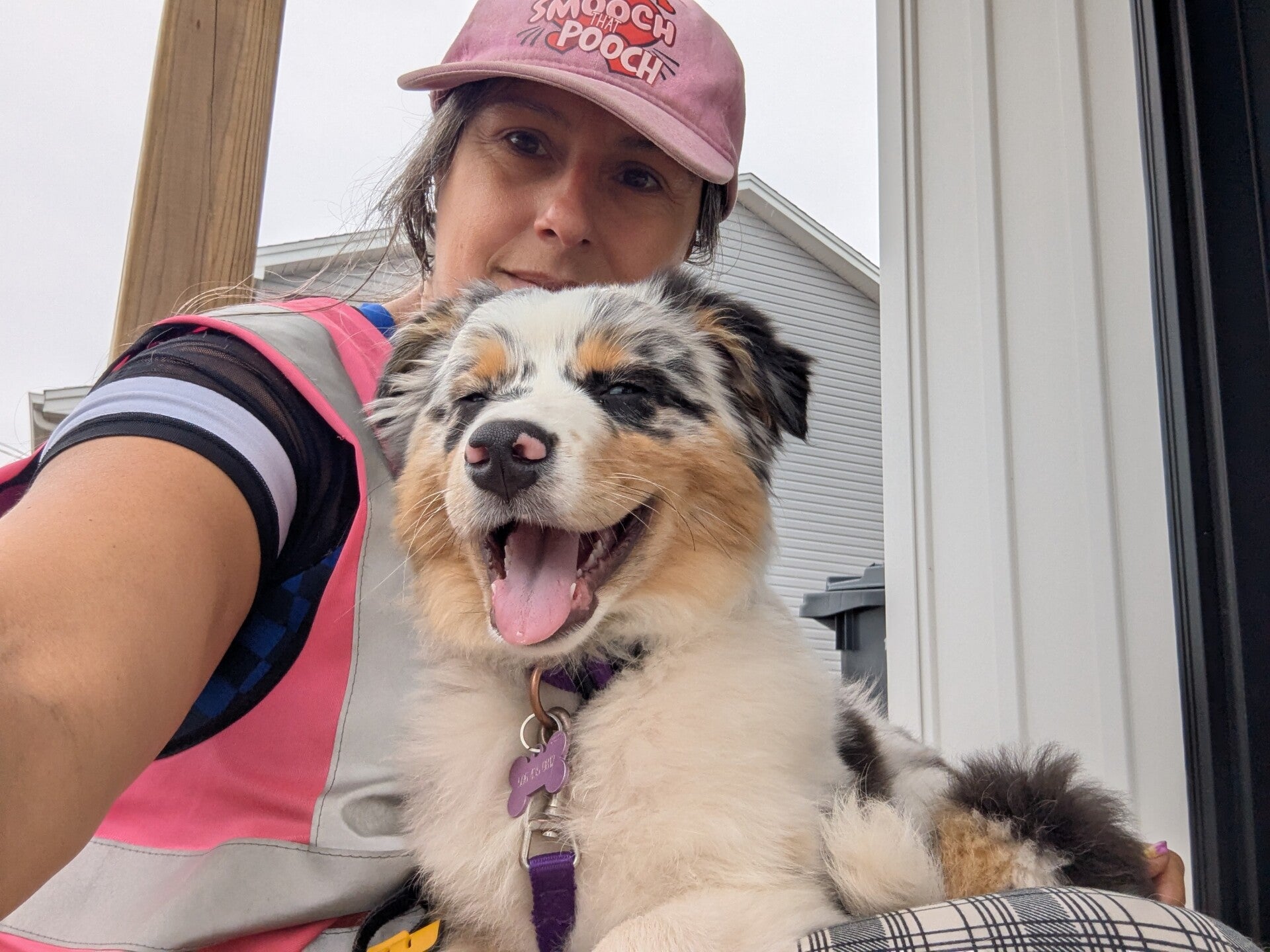 Smiling person posing with a happy white and brown dog